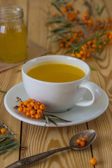 Tea with sea-buckthorn orange berries in a cup and organic honey