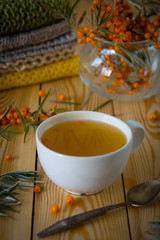 Tea with sea-buckthorn orange berries in a cup. Autumn still life