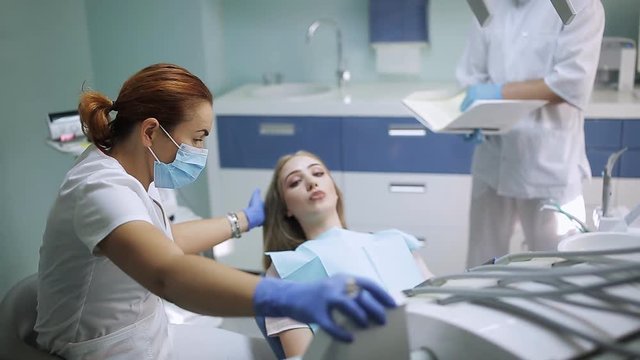 female dentist checking patient girl teeth. dentist with mirror checking patient girl teeth up at dental clinic office