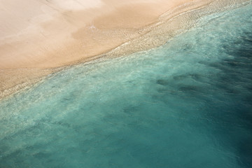 Aerial view of the tidal waves reaching the empty sandy beach on Bali