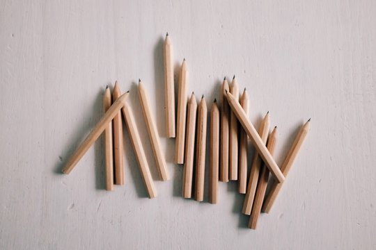 A group of small brown pencils arranged on a white table