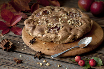 Apple pie charlotte with cinnamon and nuts. Autumn concept on rustic wooden background. Selective...
