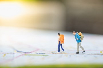 Travel Concept. Two traveler male and female miniature figures with backpack walking on map.