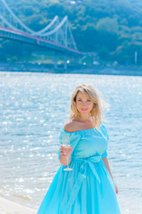 A middle-aged woman, plus in a light blue dress, rests on a city waterfront on a day off. The concept of femininity and romance in the city bustle