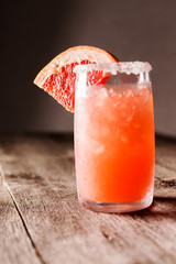 Grapefruit cocktail with ice and salt on a wooden background. Party time