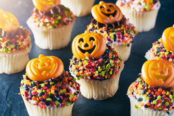 festive halloween pumpkin cupcakes with chocolate frosting and colorful sprinkles