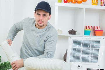 handsome technician installing air-conditioner in building