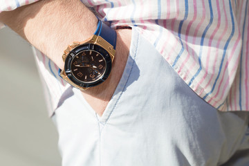  fashion image of luxury watch on wrist of man.body detail of casual look.Man's hand in blue pants...