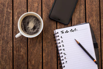 To do list in the diary with a phone and coffee in a mug.