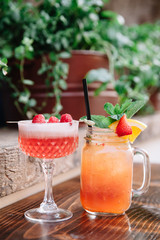 Two alcoholic cocktails garnished with berries and mint