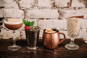 A variety of four alcoholic cocktails against white brick background