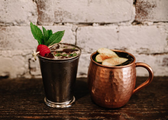 Mint julep and moscow mule cocktails against white brick background