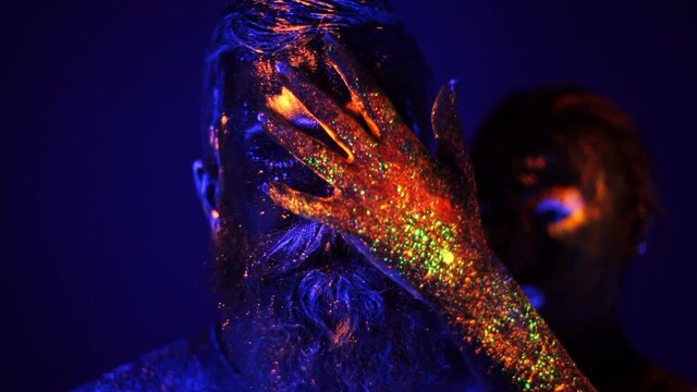 Portrait of a bearded man and woman painted in ultraviolet powder