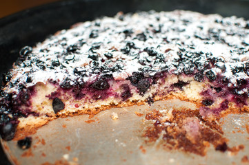 Blackcurrant tart with sugar powder on a round baking tray