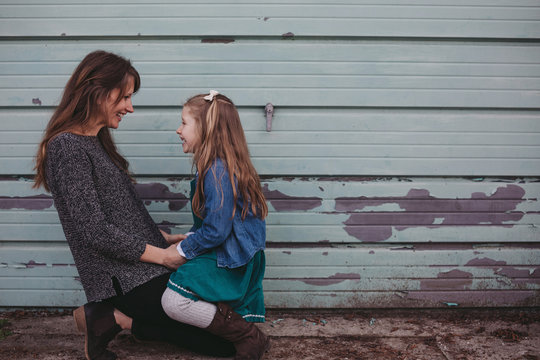 Young mother enjoying her daughter outside near blue green wall