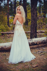 Obraz na płótnie Canvas Romantic tender bride in a white dress in the forest. The concept of a wedding in a rustic style. Beauty of the bride in combination with forest and nature, wedding fashion and dress elements