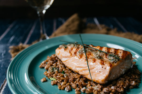Salmon fillet on top of spelt wheat and a glass of white wine