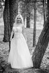 Fototapeta na wymiar Romantic tender bride in a white dress in the forest. The concept of a wedding in a rustic style. Beauty of the bride in combination with forest and nature, wedding fashion and dress elements