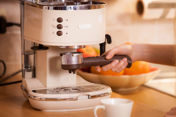 Woman in kitchen making coffee from machine