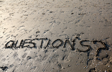 Text QUESTIONS with question mark written on the sand