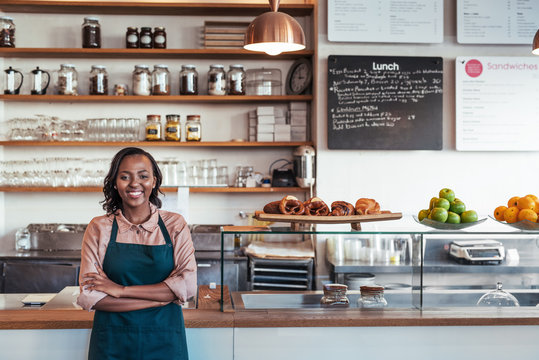 Smiling young African entrepreneur standing at her bakery counter