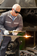 Senior metalworker using gas torch