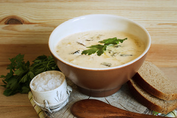 Serving soup from forest mushrooms in a rural style. Natural wood background. Selective focus. Horizontal.