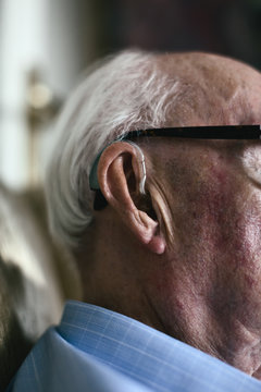 Closeup of an elderly man with a hearing aid.