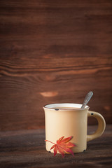 Vintage cup of coffee with a maple leaf on wooden background