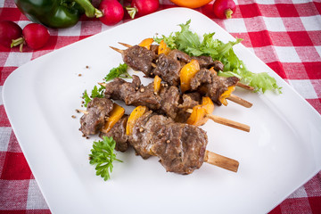Lamb skewers on plate with vegetables