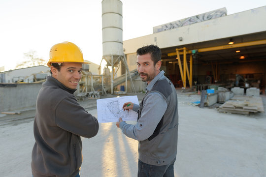 Workmen Looking At Plans On Worksite