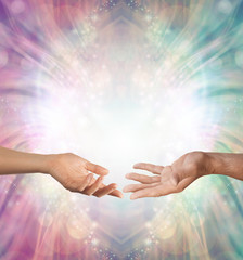 Male and Female energy merging - a female hand and a male hand with open palms facing each other against a beautiful intricate masculine and feminine colored energy background with copy space above
