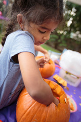 A little girl carving a pumpkin