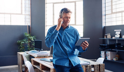 Businessman talking on his cellphone and using a digital tablet