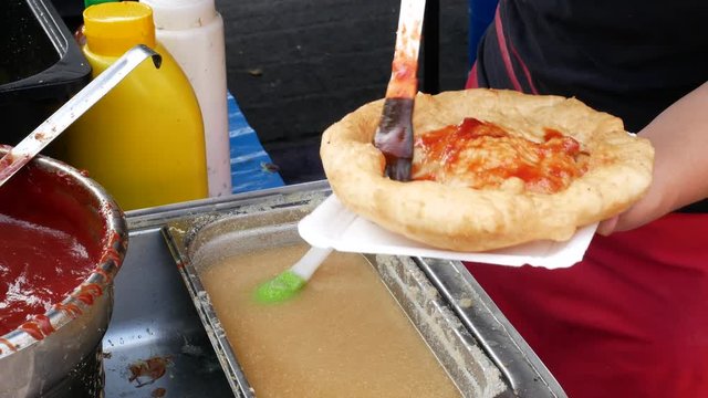Langos is a Hungarian food speciality. Pasta fried plate with ketchup, cheese and garlic water.