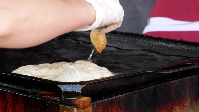 Langos is a Hungarian food speciality. Fried dough in oil. Traditional street food from the stand.