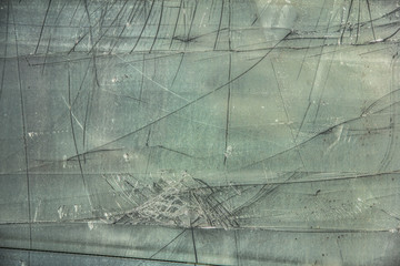Damaged, broken glass sheet with black cracks on green background 