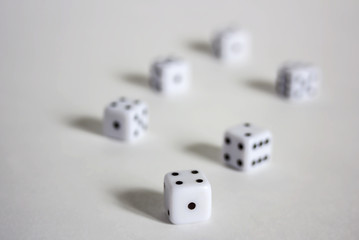 White dices in a row or scattered on white background soft focus