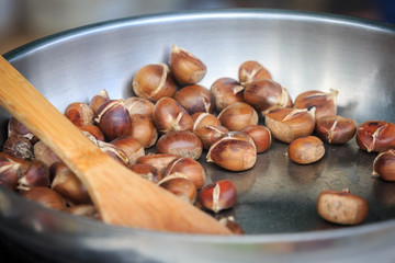 Warm fried edible chestnuts (castanea sativa) lie in a frying pan