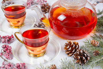 two cups of tea with tea pot and decoration on snow in winter