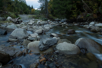 mountain river with stones, forest and rocks background 