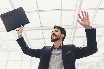 Young businessman on the background of the panoramic Windows raised hands up