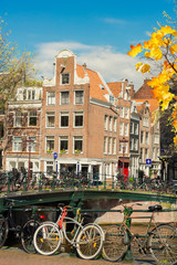 Fototapeta na wymiar Houses and bicycles standing next to canal in Amsterdam, Netherlands at autumn day