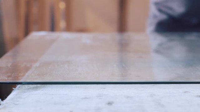 man cutting glass with glass cutter