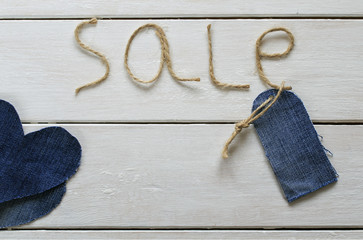 original background with a stylish inscription from sale of twine in my hand, a blank price tag and hearts of denim