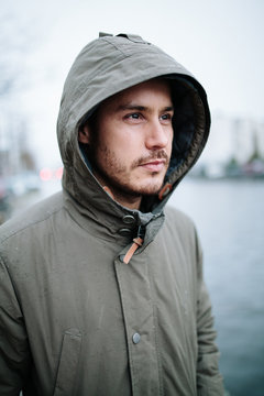 Portrait of a lonely man standing next to an inner city canal during bad weather