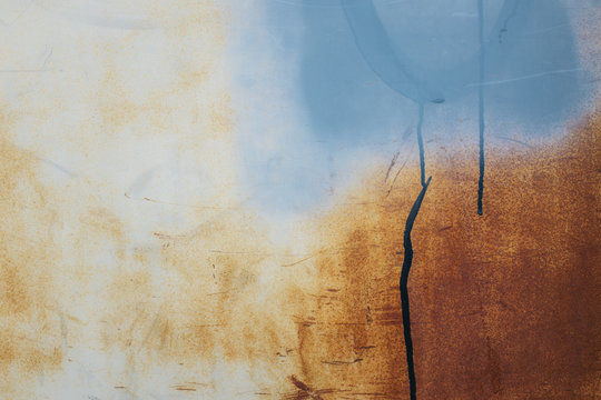 Blue paint covering graffiti tags on rusty, metal wall, close up