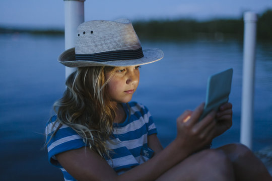 Teen Girl Texting on Cell phone While sitting on Dock