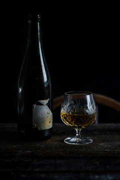Vintage sherry bottle and crystal glass in natural low light setting.