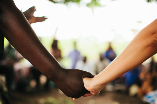 African Woman and American Woman Hold Hands in Uganda